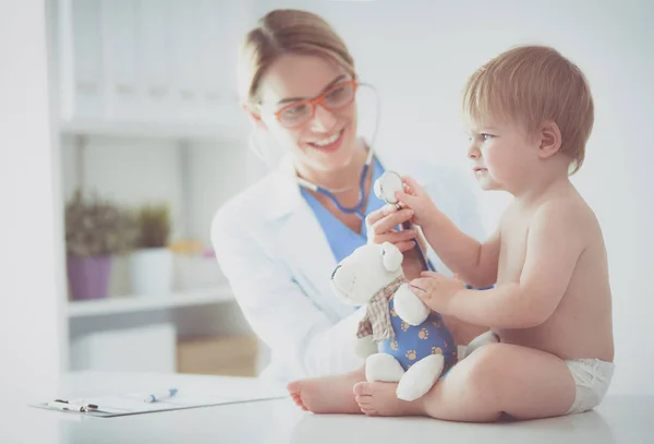 Женщина-врач слушает ребенка со стетоскопом в клинике — стоковое фото