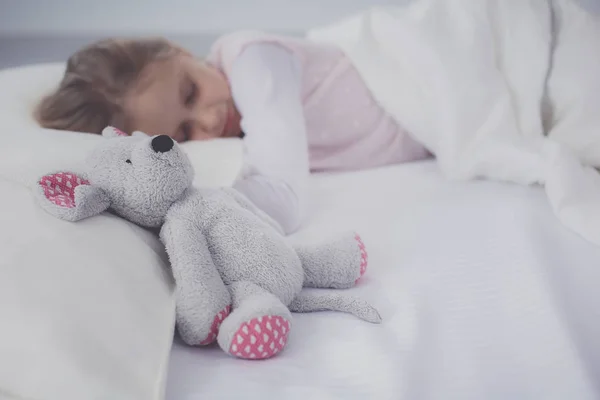 Bambino bambina dorme nel letto con un orsacchiotto giocattolo . — Foto Stock