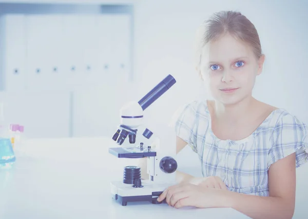 Colegiala mirando a través del microscopio en la clase de ciencias . — Foto de Stock