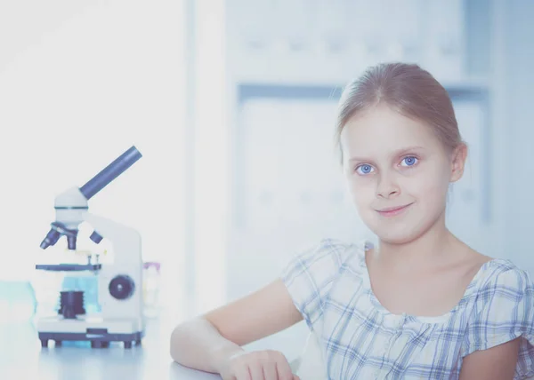 Colegiala mirando a través del microscopio en la clase de ciencias . — Foto de Stock