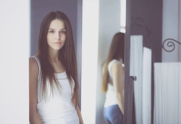 Mujer joven mirándose a sí misma reflejo en el espejo en casa . — Foto de Stock
