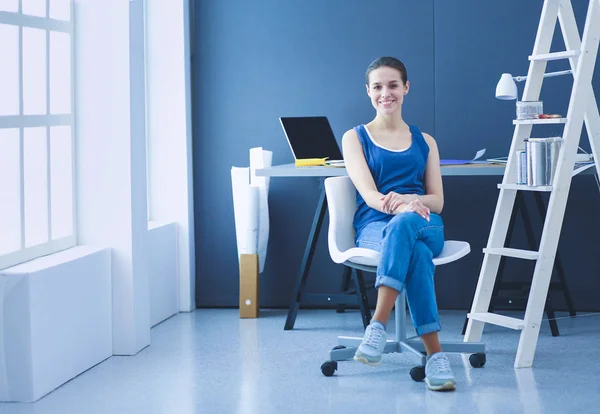 Mujer joven sentada en el escritorio con instrumentos, plano y portátil. — Foto de Stock