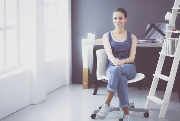 Ung kvinna sitter vid skrivbordet med instrument, plan och laptop. — Stockfoto