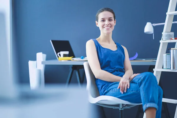 stock image Young woman sitting at the desk with instruments, plan and laptop.