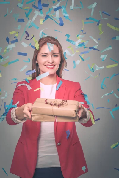 Beautiful happy woman with gift box at celebration party with confetti . Birthday or New Year eve celebrating concept