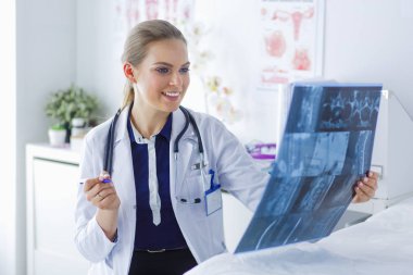 Genç ve çekici bayan doktor röntgen görüntülerine bakıyor.