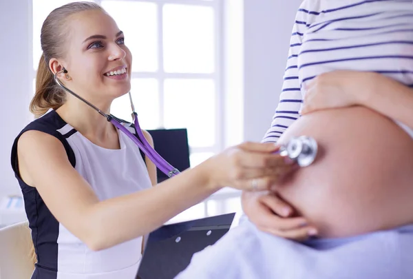Mladá žena lékař se stetoskopem a tablet mluvit s těhotnou ženou v nemocnici. — Stock fotografie