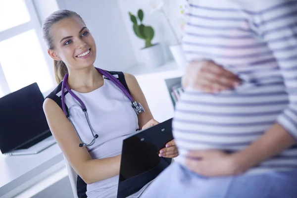 Doctora joven con estetoscopio y tableta que habla con una mujer embarazada en el hospital. —  Fotos de Stock