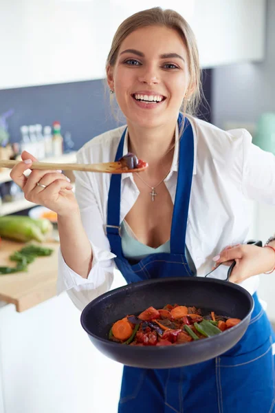 Jeune femme debout près de la cuisinière dans la cuisine — Photo