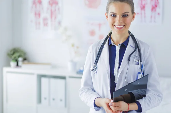 Улыбающаяся женщина-врач с папкой в форме стоя — стоковое фото