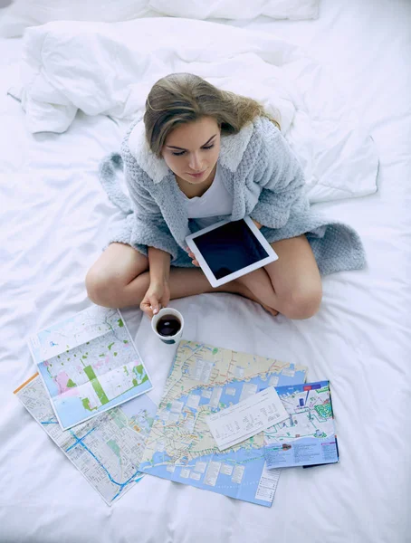 Entspannte junge Frau sitzt mit einer Tasse Kaffee und digitalem Tablet im Bett — Stockfoto