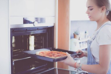 Mutlu genç bayan evde pizza pişiriyor.