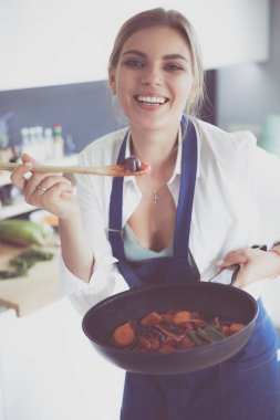 Mutfakta sobanın yanında duran genç bir kadın..