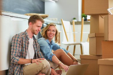 Genç bir çift yeni ev içinde hareket. Oturma ve açma sonra rahatlatıcı. Bir şey üstünde laptop arıyorum. Genç Çift