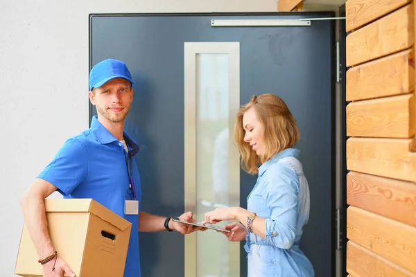 stock image Smiling delivery man in blue uniform delivering parcel box to recipient - courier service concept. Smiling delivery man in blue uniform