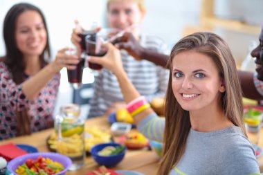 Ahşap masada otururken birlikte yemek yiyen bir grup insanın üst düzey görüntüsü. Masada yemek var. İnsanlar fast food yiyor. Bir kızın portresi.