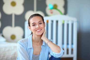 Çocuk karyolası yakın katta oturan bir genç bayan. Genç anne.