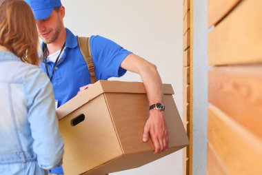 Mavi üniformalı gülümseyen kurye servis konseptine paket kutusu teslim eden teslimatçı. Mavi üniformalı gülümseyen teslimatçı.
