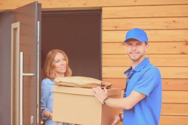 Mavi üniformalı gülümseyen kurye servis konseptine paket kutusu teslim eden teslimatçı. Mavi üniformalı gülümseyen teslimatçı.
