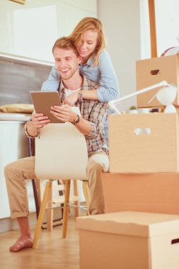 Genç bir çift yeni ev içinde hareket. Oturma ve açma sonra rahatlatıcı. Bir şey üstünde laptop arıyorum. Genç Çift