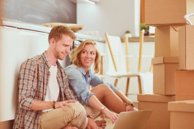 Genç bir çift yeni ev içinde hareket. Oturma ve açma sonra rahatlatıcı. Bir şey üstünde laptop arıyorum. Genç Çift