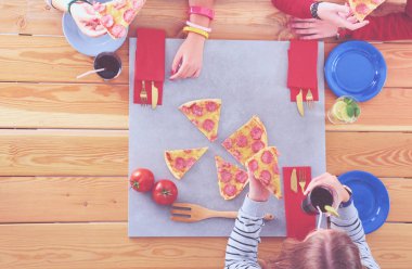 Ahşap masada otururken birlikte yemek yiyen bir grup insanın üst düzey görüntüsü. Masada yemek var. İnsanlar fast food yiyor..