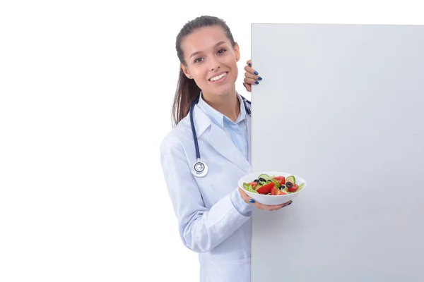 Retrato de una hermosa doctora sosteniendo un plato con verduras frescas en blanco. Mujeres doctores — Foto de Stock