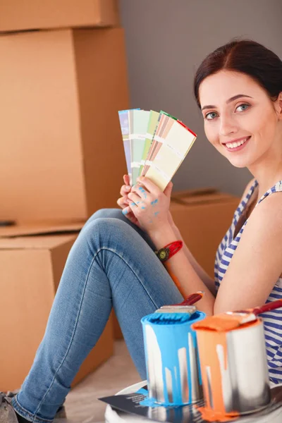 Kadın seçerek boya rengi renk örneği yeni ev ahşap yere oturmak için. Kadın evde
