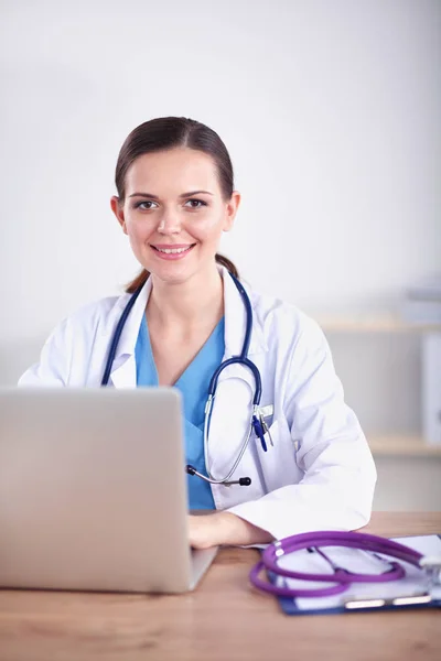 Όμορφη νεαρός χαμογελαστό γυναίκα γιατρό κάθεται στο γραφείο και το γράψιμο. γυναίκα γιατρό — Φωτογραφία Αρχείου