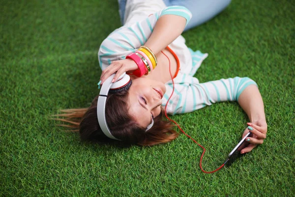 Mooie jonge vrouw die selfie maakt door haar telefoon terwijl ze in groen gras ligt. mooie jonge vrouw maken selfie — Stockfoto