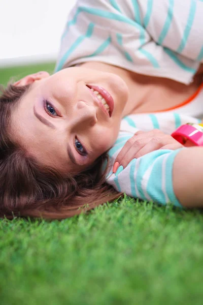 Güzel genç bir kadın yeşil çimlerin üzerinde yatıyor. — Stok fotoğraf
