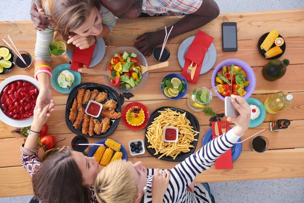 Vista superior do grupo de pessoas que jantam juntas enquanto estão sentadas à mesa de madeira. Comida na mesa. As pessoas comem fast food. — Fotografia de Stock