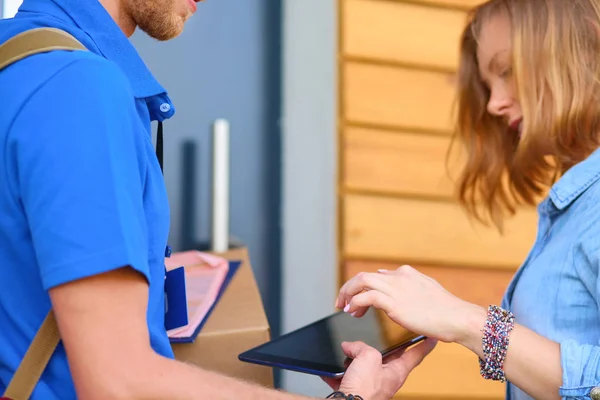 Repartidor sonriente con uniforme azul que entrega la caja de paquetes al destinatario: concepto de servicio de mensajería. Repartidor sonriente en uniforme azul — Foto de Stock