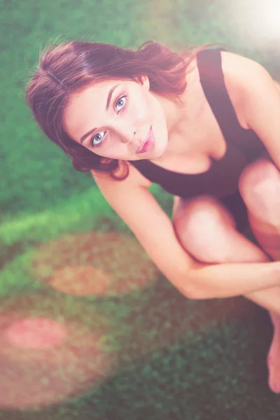 Vrouw zitten met gekruiste benen op het groene gras. — Stockfoto