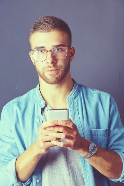 Sorrindo jovem segurando telefone enquanto mensagens de texto — Fotografia de Stock