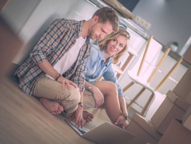 Genç bir çift yeni ev içinde hareket. Oturma ve açma sonra rahatlatıcı. Bir şey üstünde laptop arıyorum. Genç Çift