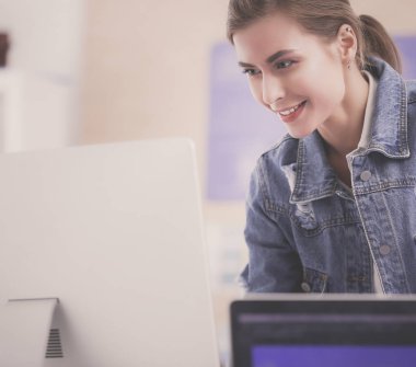 Enstrümanlar, planlar ve dizüstü bilgisayarlarla masanın yanında duran genç bir kadın..