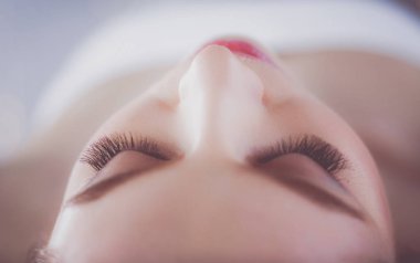 Masaj masasında uzanmış gözleri kapalı rahatlayan genç bir kadın. - Kadın. Spa salonu