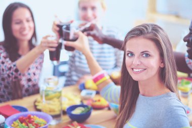 Ahşap masada otururken birlikte yemek yiyen bir grup insanın üst düzey görüntüsü. Masada yemek var. İnsanlar fast food yiyor. Bir kızın portresi.