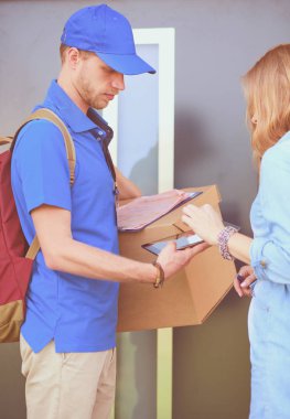 Mavi üniformalı gülümseyen kurye servis konseptine paket kutusu teslim eden teslimatçı. Mavi üniformalı gülümseyen teslimatçı.