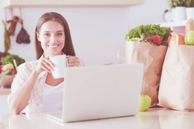 Mutfakta tablet ve kredi kartı kullanan gülümseyen bir kadın. Gülümseyen kadın