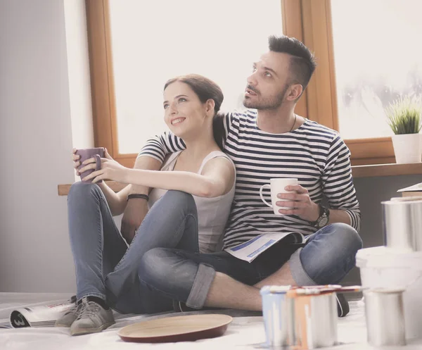 Retrato feliz sonriente joven pareja pintando la pared interior de la casa nueva. Pareja joven — Foto de Stock