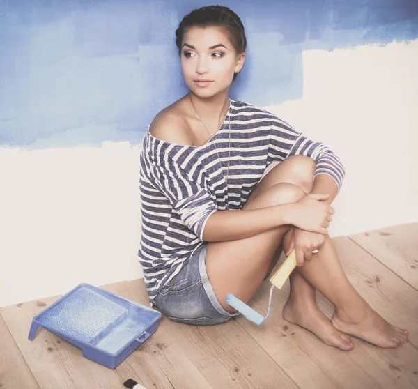 Portrait of female painter sitting on floor near wall after painting — Stock Photo, Image