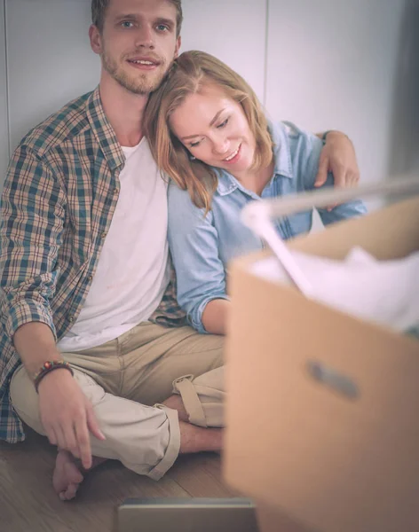 Unga par som flyttar i nya hem. Sitter och avkopplande efter uppackning. Ser något på laptop. Ungt par — Stockfoto