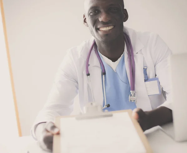 Portret van een jonge mannelijke arts die een headset draagt terwijl hij een computer gebruikt aan een bureau in de kliniek. Dokter.. — Stockfoto