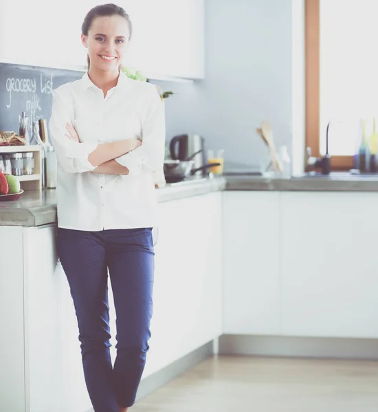 Retrato de mujer joven de pie con los brazos cruzados sobre el fondo de la cocina. Mujer en la cocina . —  Fotos de Stock