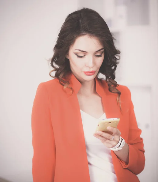 Bella donna d'affari utilizzando il telefono cellulare in piedi in ufficio — Foto Stock