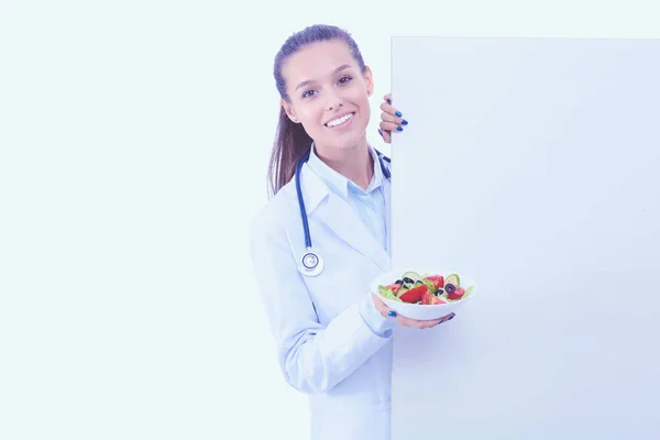 Retrato de una hermosa doctora sosteniendo un plato con verduras frescas en blanco. Mujeres doctores —  Fotos de Stock