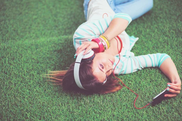 Mooie jonge vrouw die selfie maakt door haar telefoon terwijl ze in groen gras ligt. mooie jonge vrouw maken selfie — Stockfoto