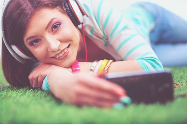 Vacker ung kvinna gör selfie vid sin telefon när hon ligger i grönt gräs. Vacker ung kvinna gör selfie — Stockfoto